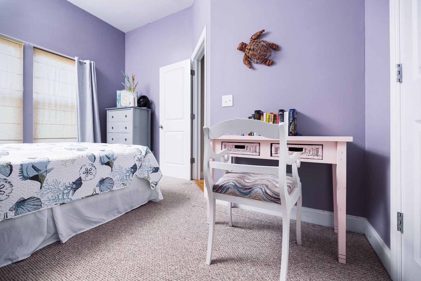 Curl up on your comfy sofa with a good book, then tackle tasks at your dedicated desk space in this charming lavender-hued room.
