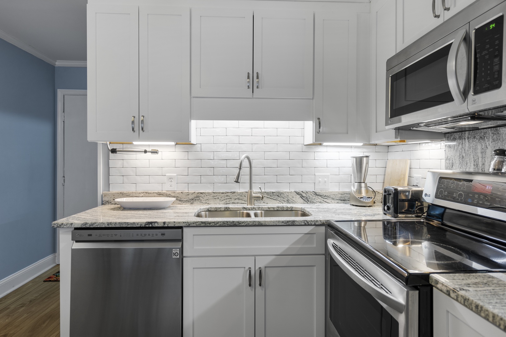 Your sleek kitchen features granite countertops, stainless steel appliances, and crisp white cabinetry with subway tile backsplash for effortless meal preparation.