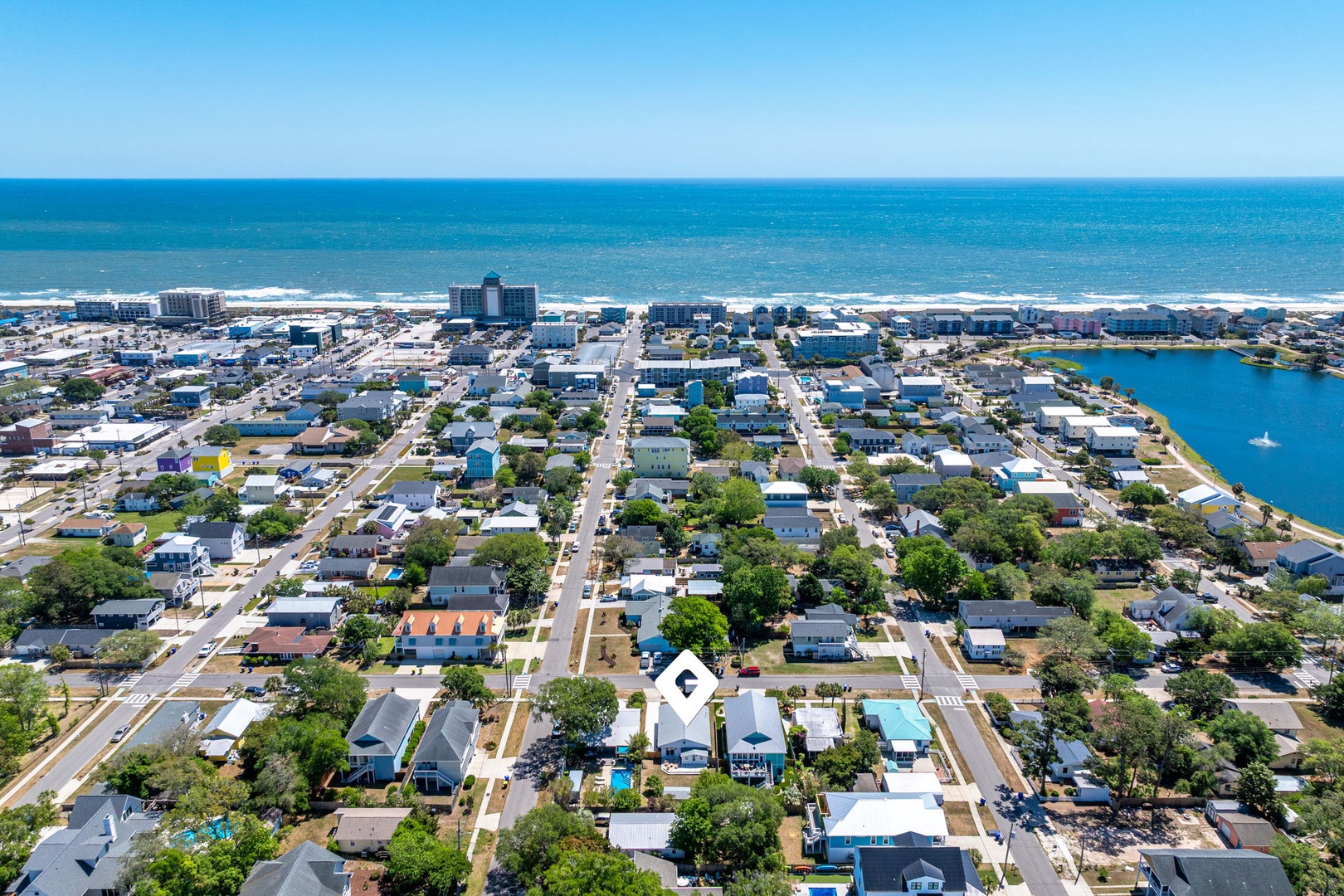 Aerial view of coastal town with beach access, featuring residential neighborhoods, lake, and ocean proximity.