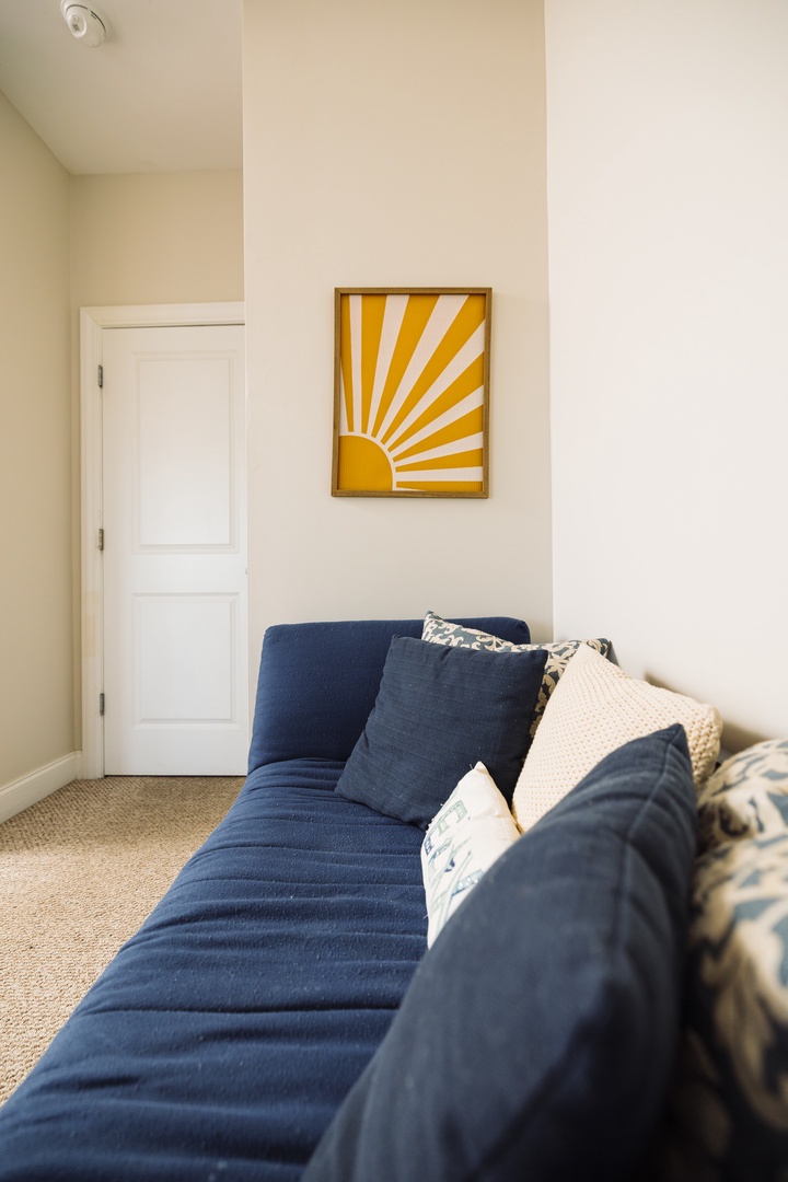 Sink into this cozy navy sofa where sunshine artwork brightens your relaxation time with soft pillows and warm neutral tones.