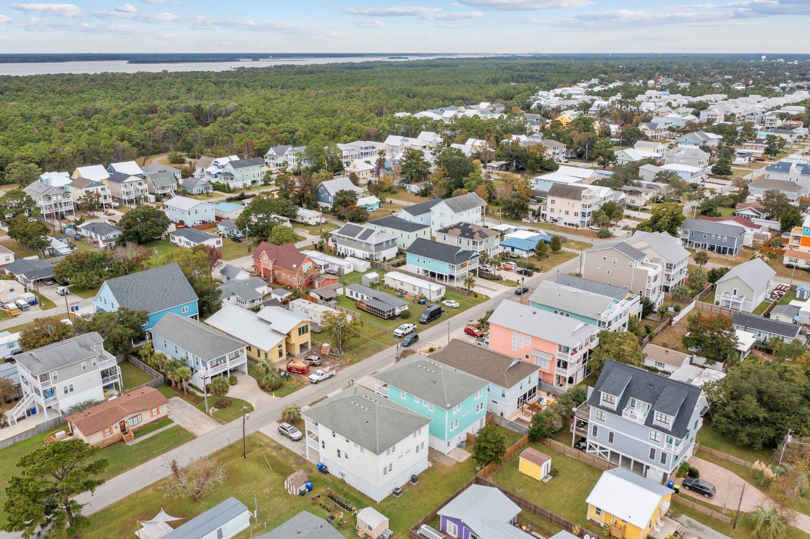 Aerial view of a charming coastal neighborhood with colorful homes nestled between lush forests and waterfront access.