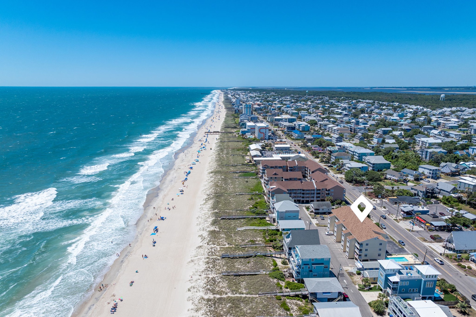 Aerial view of a pristine beachfront community with turquoise waters, white sand shores, and coastal properties nestled between the ocean and inland waterways.