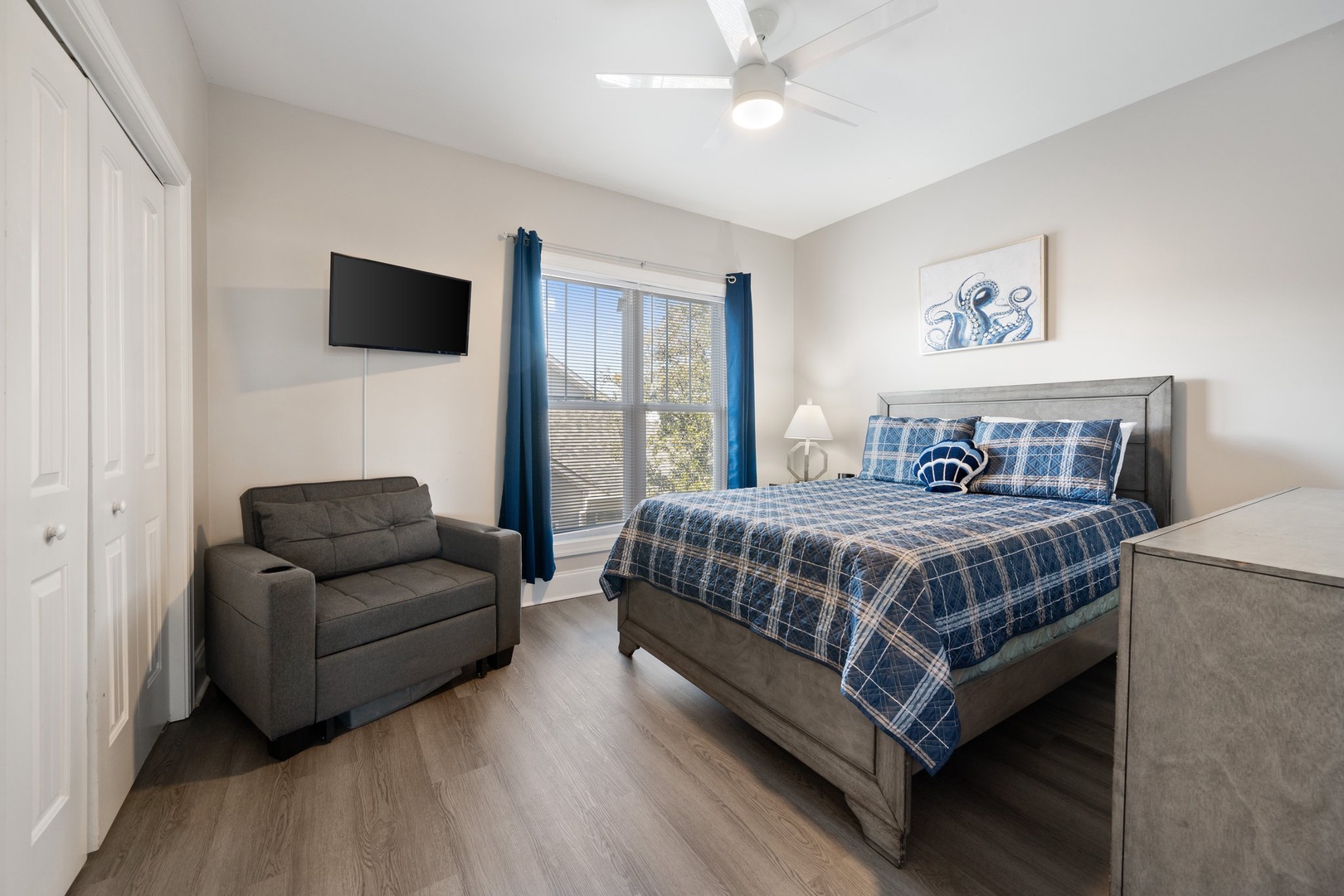 Your cozy bedroom features a comfortable chair for relaxation, wall-mounted TV for entertainment, and fresh linens awaiting your arrival.