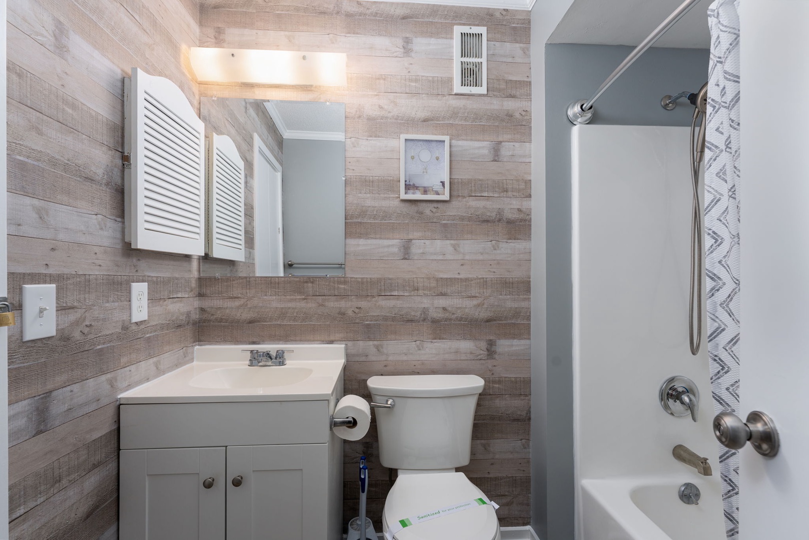 Freshen up in your cozy bathroom with modern fixtures, warm wood-plank walls, and a refreshing tub-shower combo—designed for your comfort and relaxation after a day of adventure.