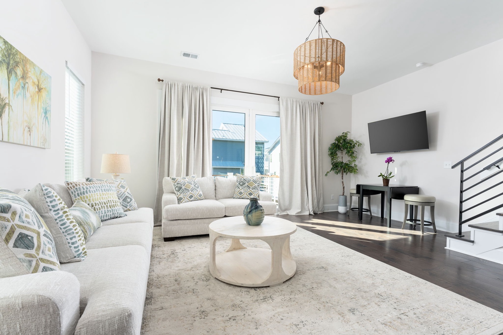 Unwind in your bright living space with plush seating, coastal artwork, and natural light streaming through large windows.