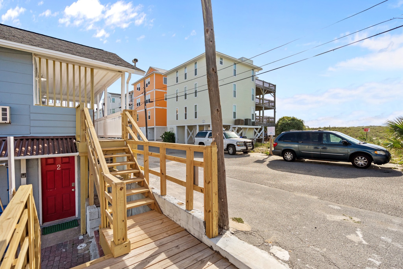 Coastal neighborhood with elevated beach houses and convenient parking area near the property entrance.
