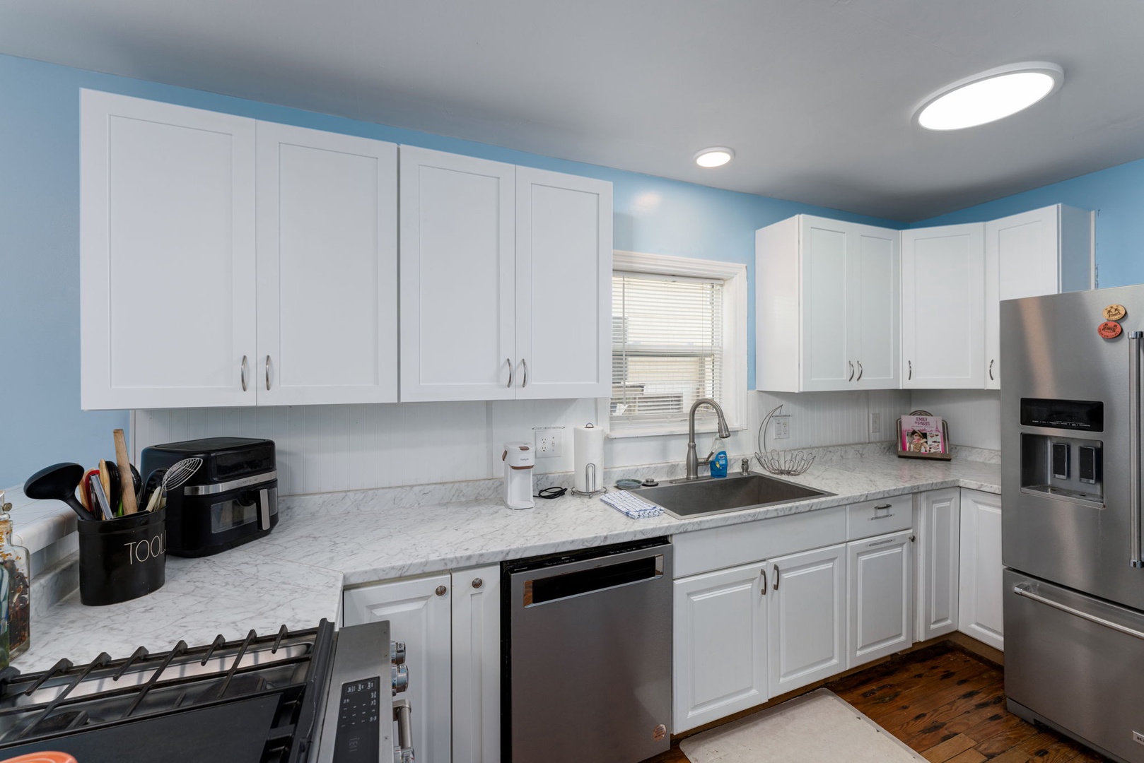You'll love preparing meals in this bright, fully equipped kitchen with modern stainless steel appliances, sleek white cabinetry, and plenty of counter space for cooking and gathering.