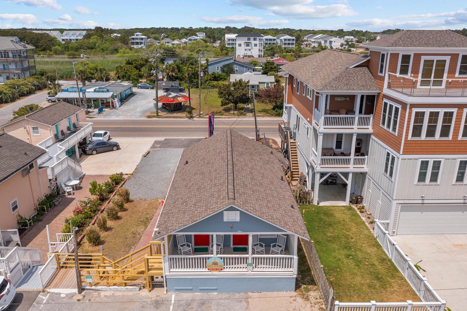 Charming coastal vacation home nestled in a friendly beach community, surrounded by tall palms and neighboring beach houses.