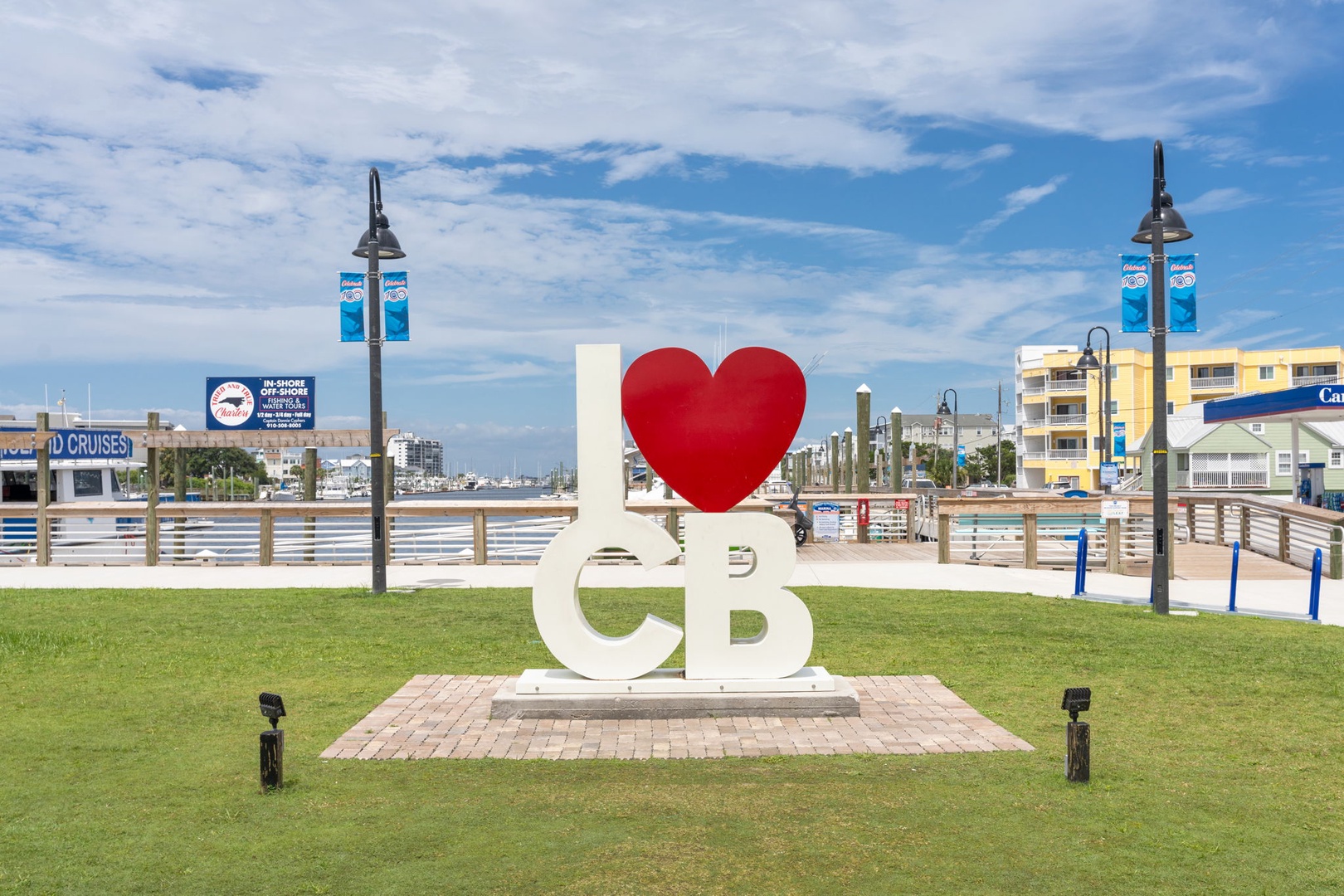 A coastal town landmark set against blue skies and waterfront, marking your arrival to a relaxed beach community with marina views and nearby amenities.