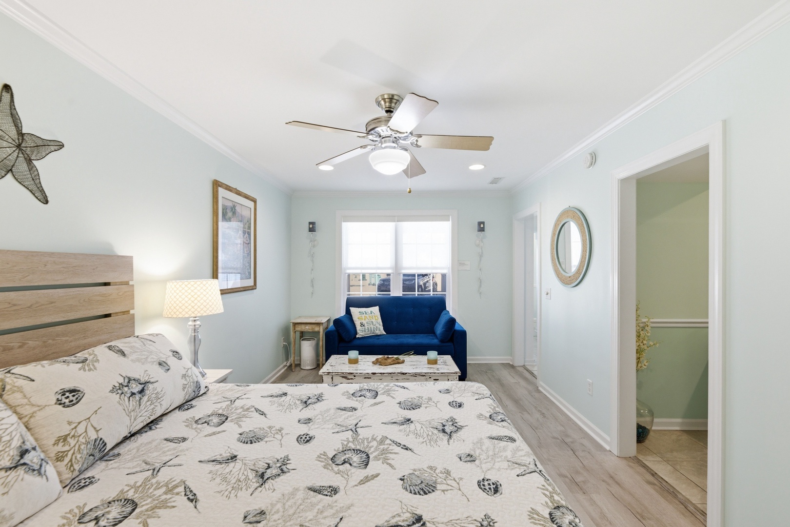 Your spacious bedroom welcomes you with coastal charm—soft blue walls, a plush bed, and a cozy seating nook by the window where you can unwind after a day of exploration.