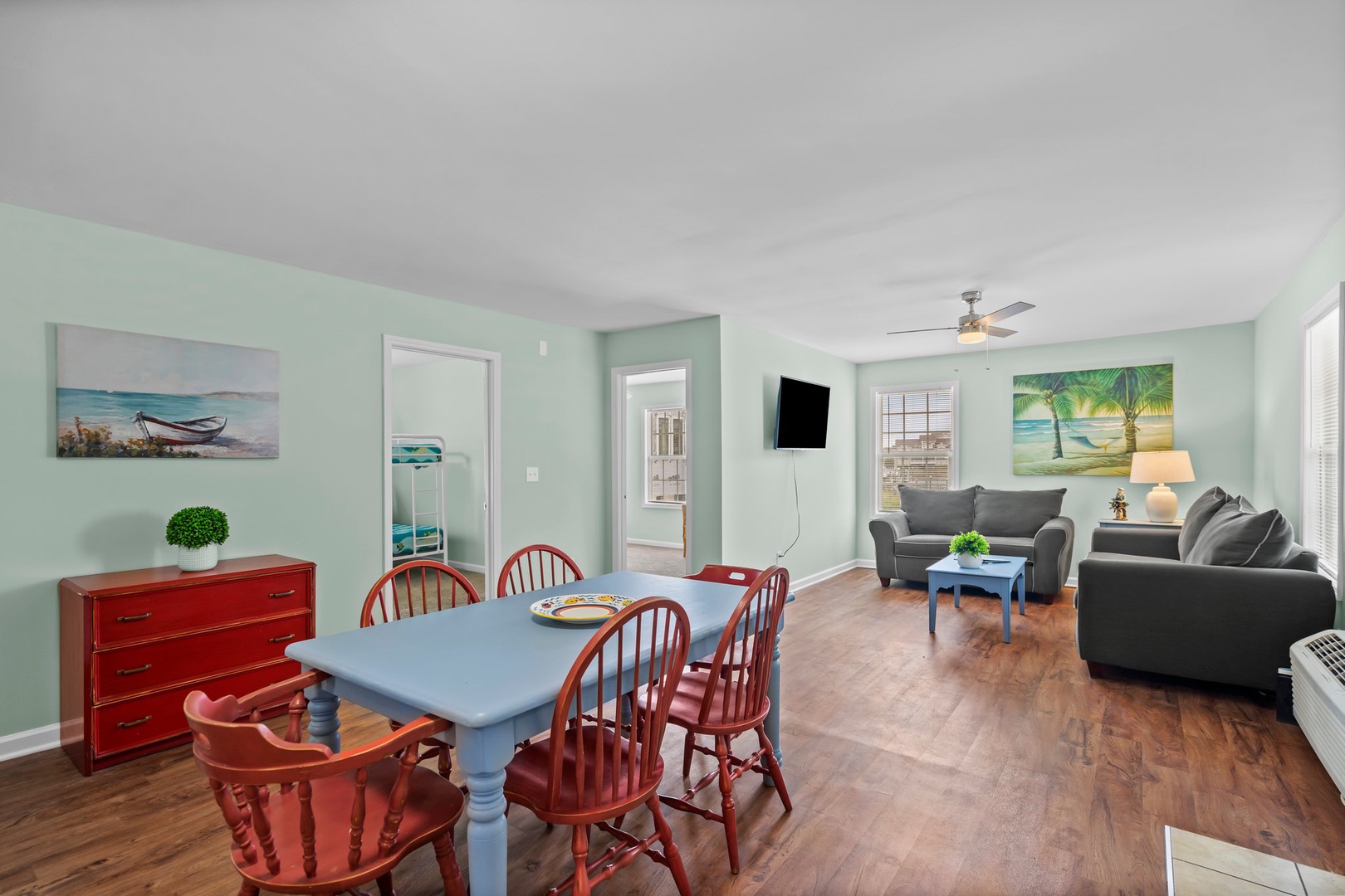 Relax in your bright, coastal-themed living space where soothing mint walls and tropical artwork create a serene beach house atmosphere.
