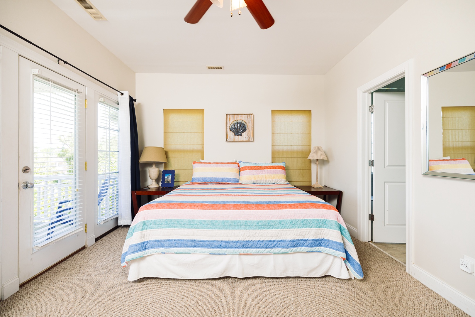 Drift off to sleep in your bright, coastal-themed bedroom with cheerful striped bedding and gentle ceiling fan breeze.