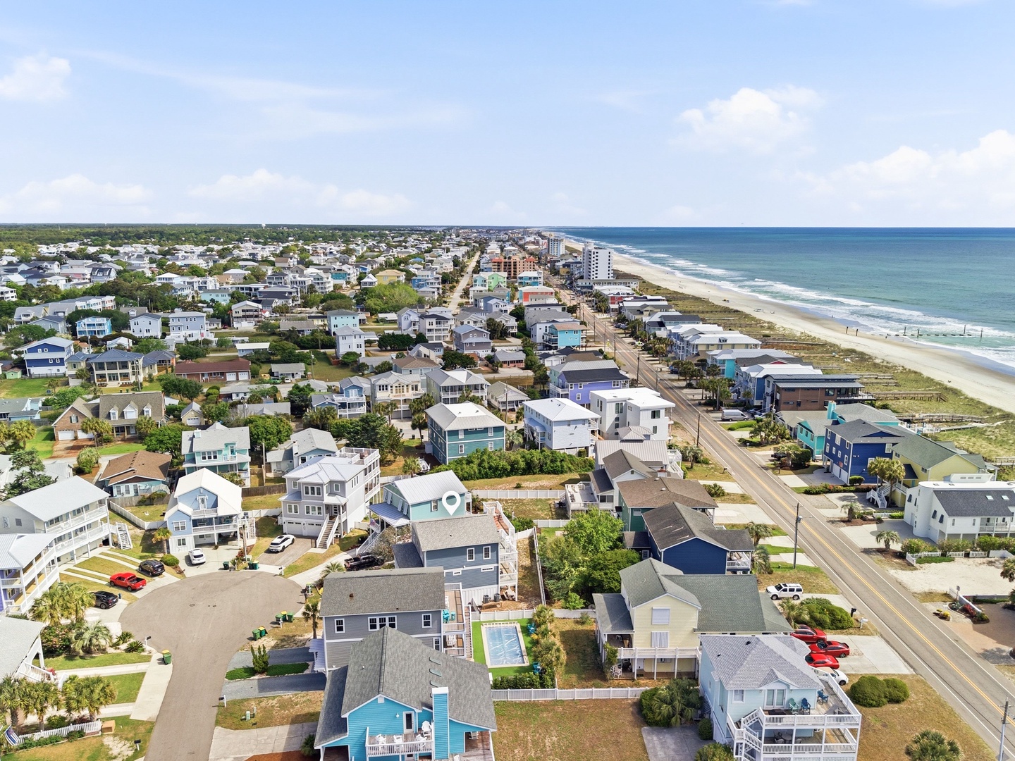 Aerial view of a coastal neighborhood with beachfront access, showcasing the property's location near the ocean and sandy shoreline.
