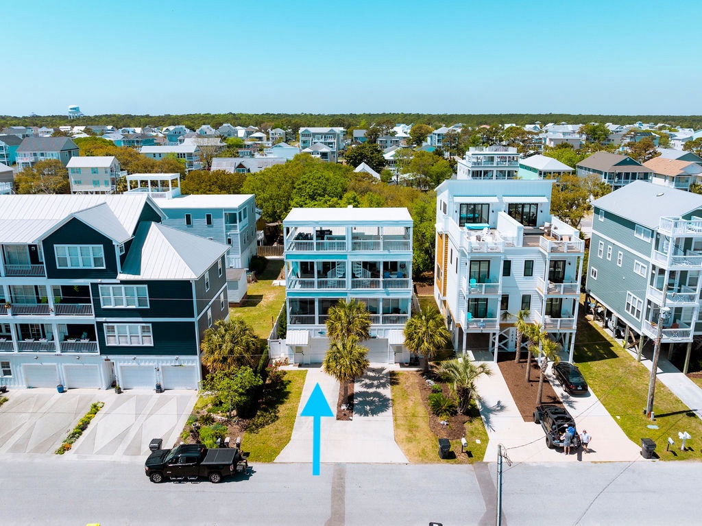 Coastal community featuring colorful beach homes with palms and tropical landscaping stretching toward the horizon.