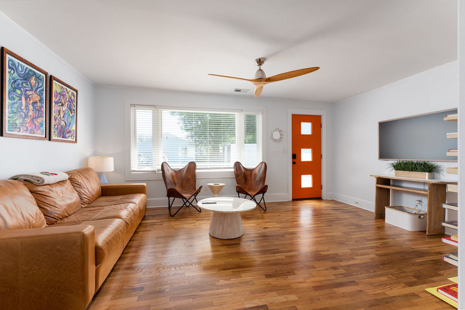 Unwind in your stylish living room with leather seating, warm wood floors, and natural light streaming through large windows.