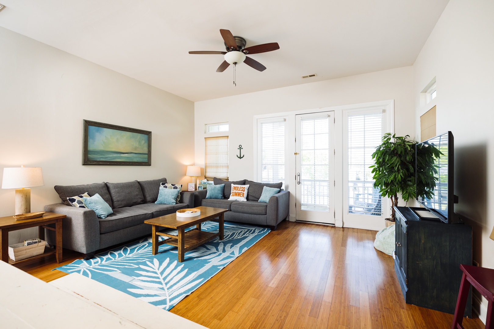 Relax in this bright living room with cozy sectional seating, coastal decor, and French doors opening to your private outdoor space.