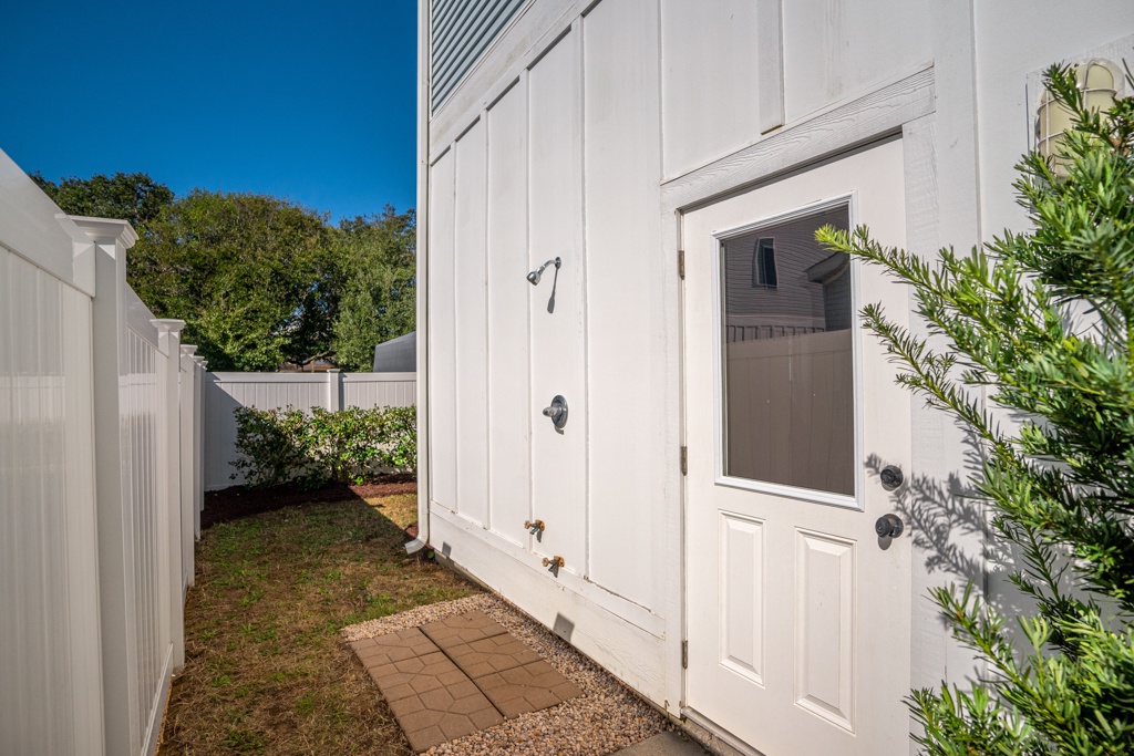 Modern white exterior features a private entrance with outdoor shower facilities in a landscaped courtyard setting.