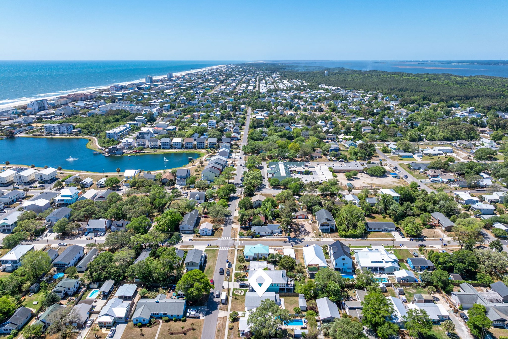 Aerial view of a charming coastal community with tree-lined streets, waterfront access, and pristine beaches stretching along the horizon.