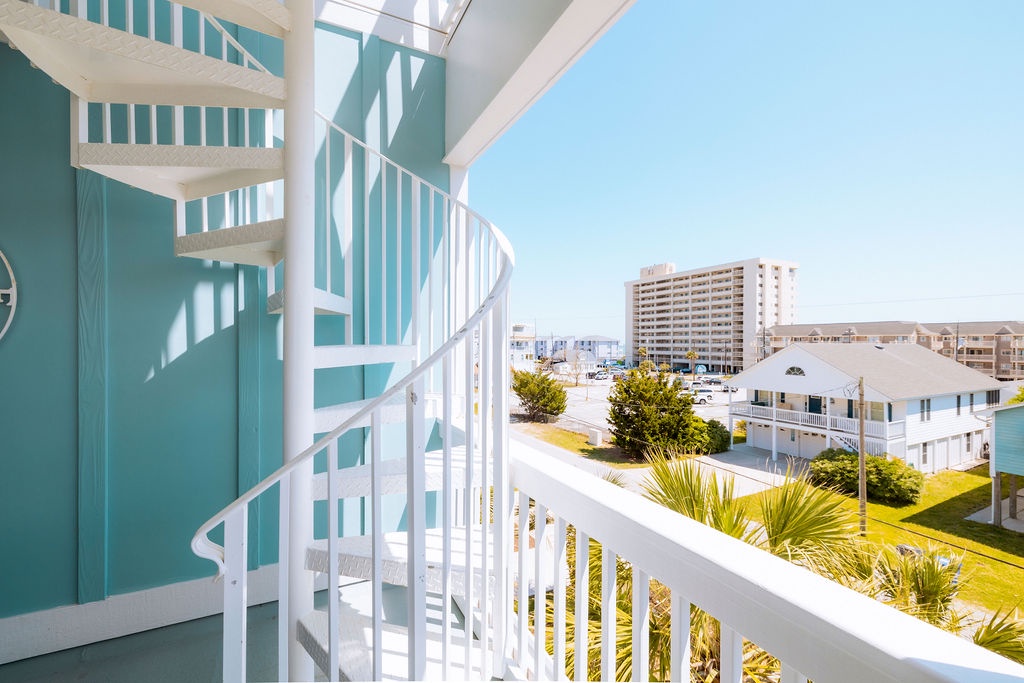 Step onto your private balcony and soak in the coastal charm with sweeping views of palm trees and colorful buildings.