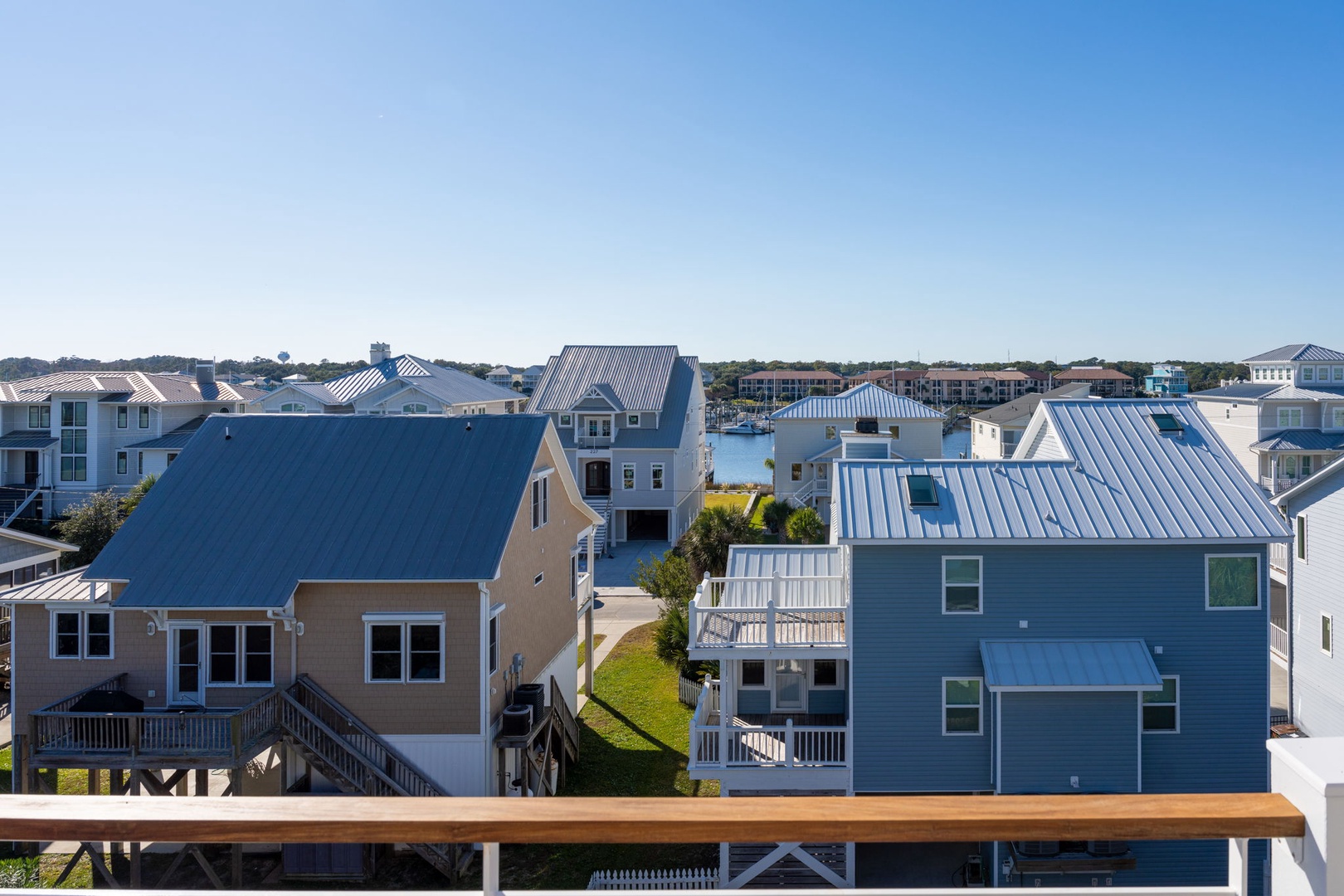 Coastal residential community with colorful beach houses and modern vacation rental properties under a clear blue sky.