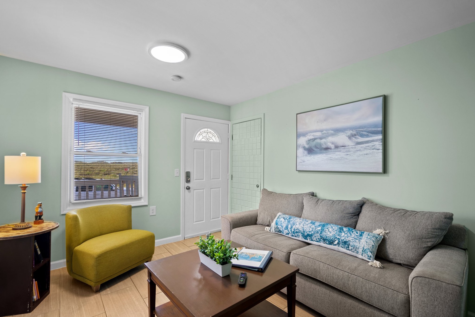 Relax in your bright living room featuring soothing mint walls, comfortable seating, and natural light streaming through the windows.