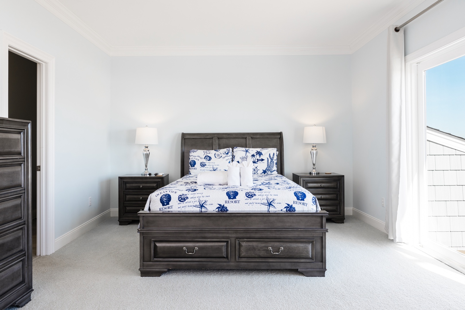 Slip into your elegant bedroom featuring nautical-themed linens and dark wood furnishings that create a serene coastal retreat.