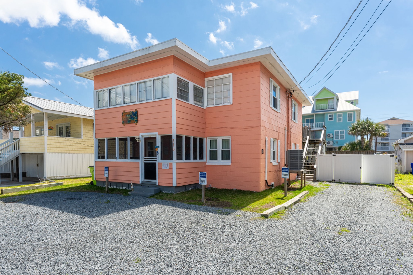 Charming coral-colored coastal property with ample parking and easy beach access, set in a vibrant seaside neighborhood beneath sunny skies.