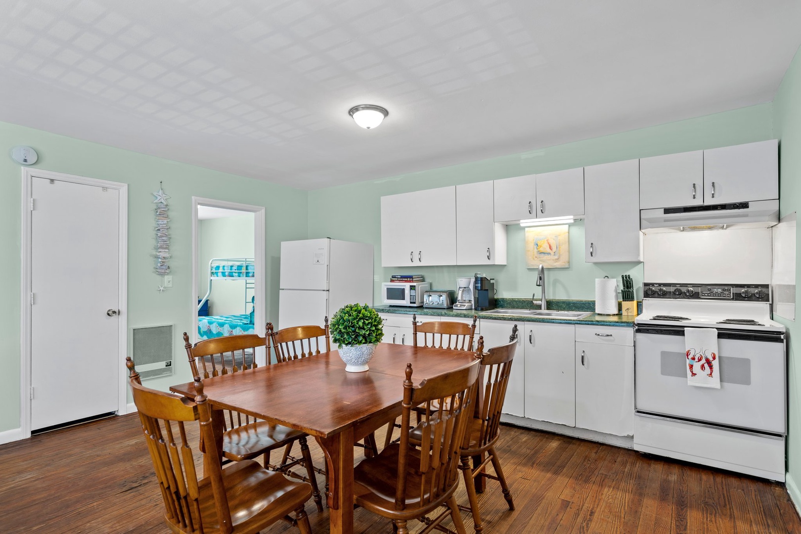 Your spacious kitchen invites memorable meals with its warm wood dining table, modern appliances, and cheerful mint walls creating the perfect gathering space.