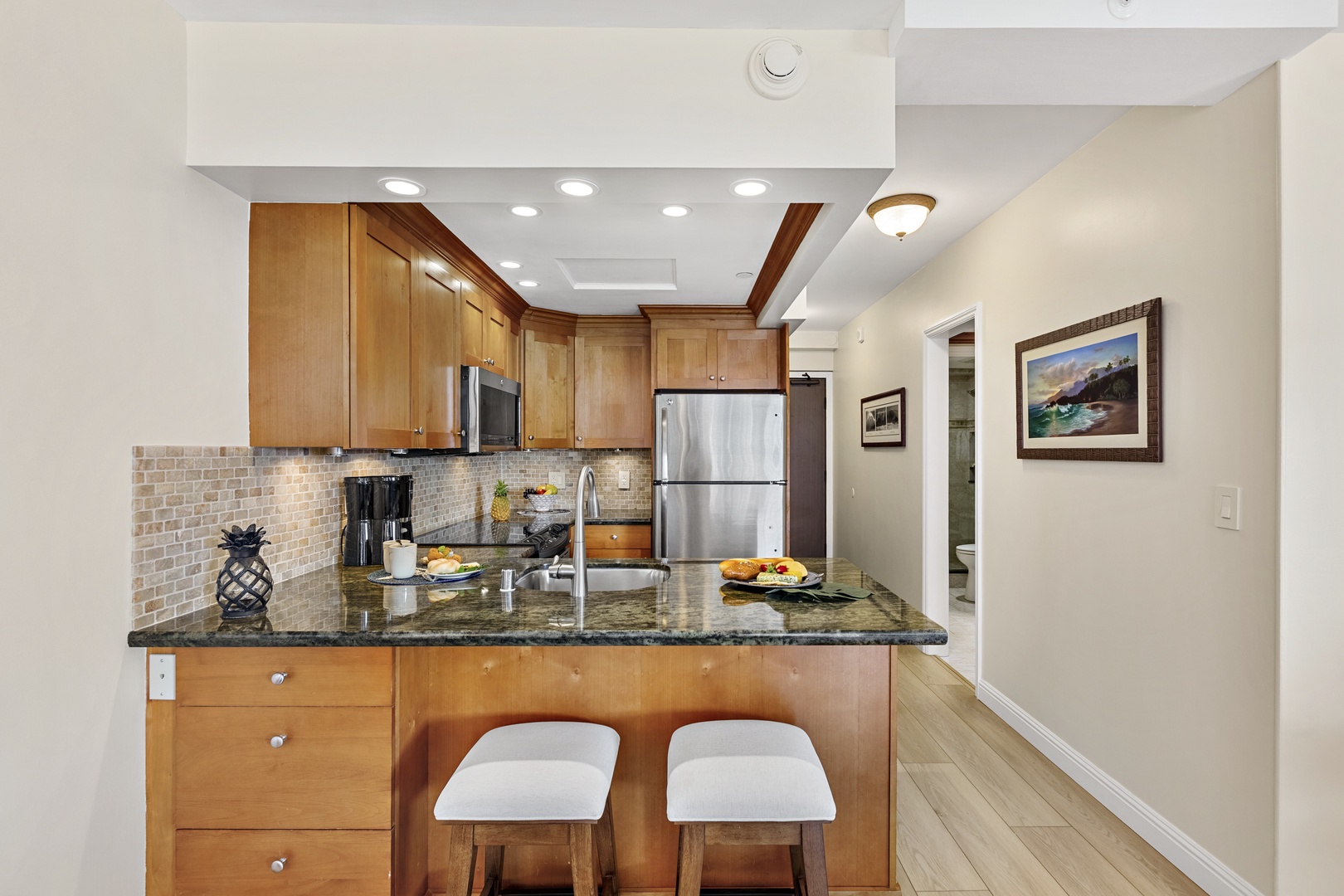Your fully equipped kitchen awaits with granite counters, stainless appliances, and cozy breakfast bar seating for morning coffee.