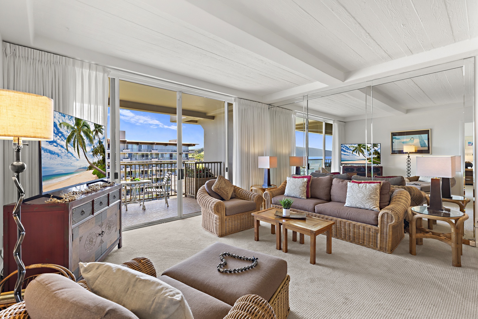 Serene coastal retreat with woven wicker furnishings, warm wood accents, and expansive glass doors flooding the space with natural light. Plush seating and airy ceiling beams create a peaceful haven.
