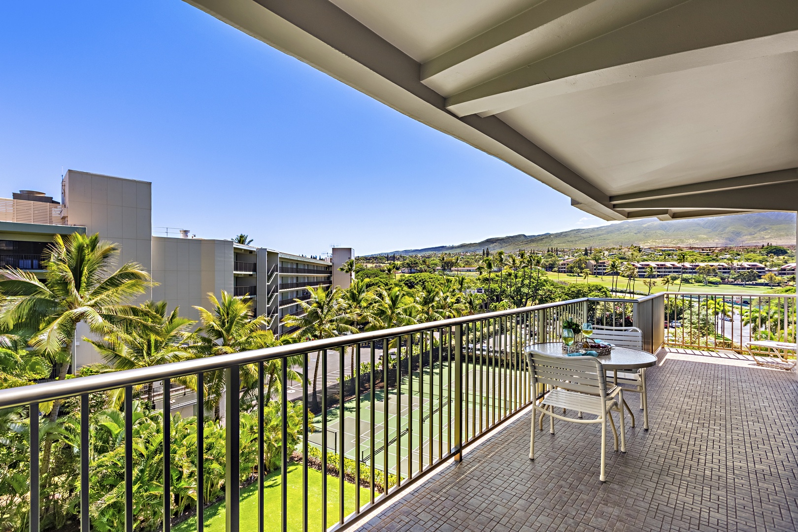 Expansive balcony with panoramic views of Kaanapali Golf Course and distant mountains, featuring comfortable seating for relaxation.