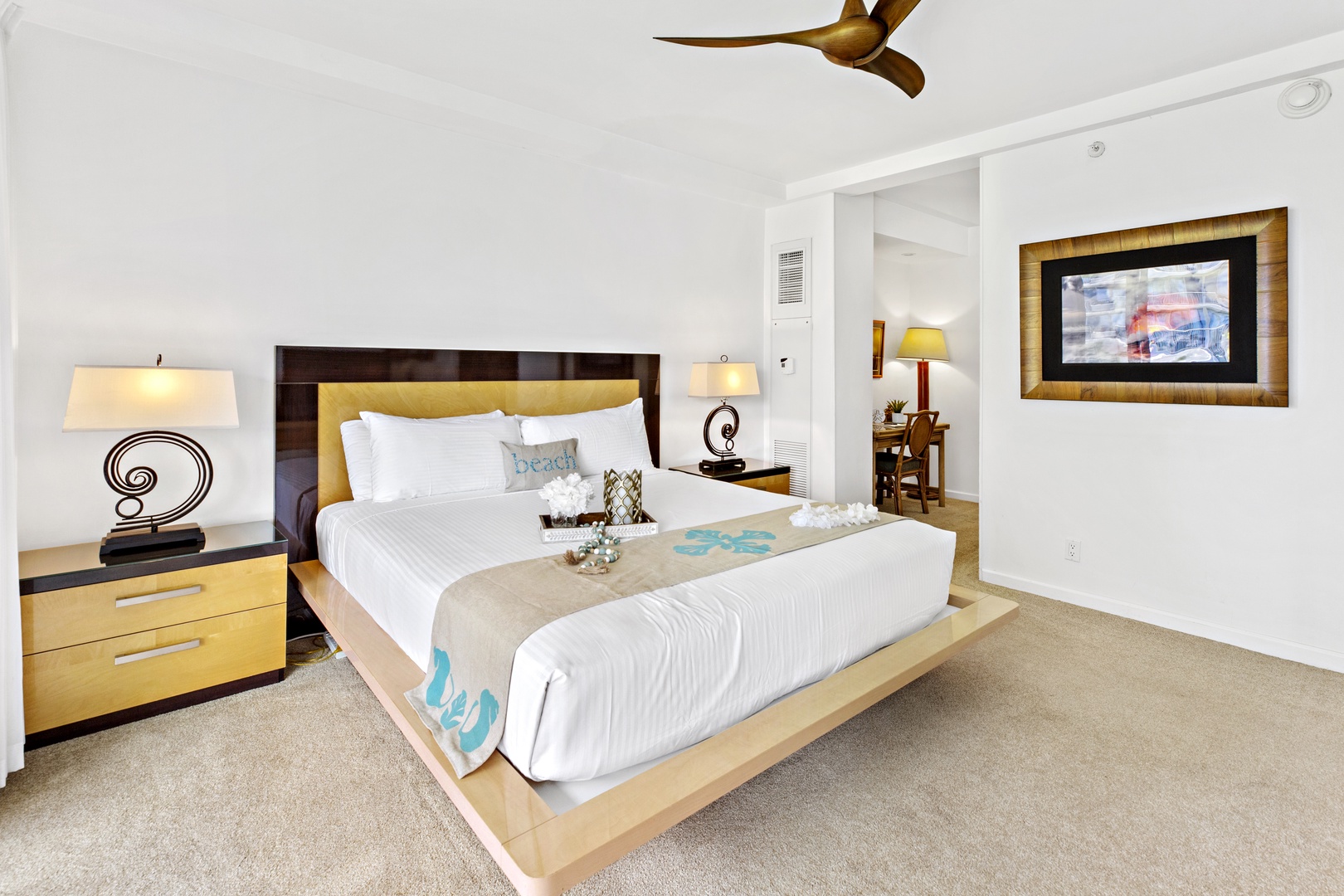 Sink into your king bed with crisp linens and tropical touches. The ceiling fan keeps you cool while stylish lamps create perfect ambiance.