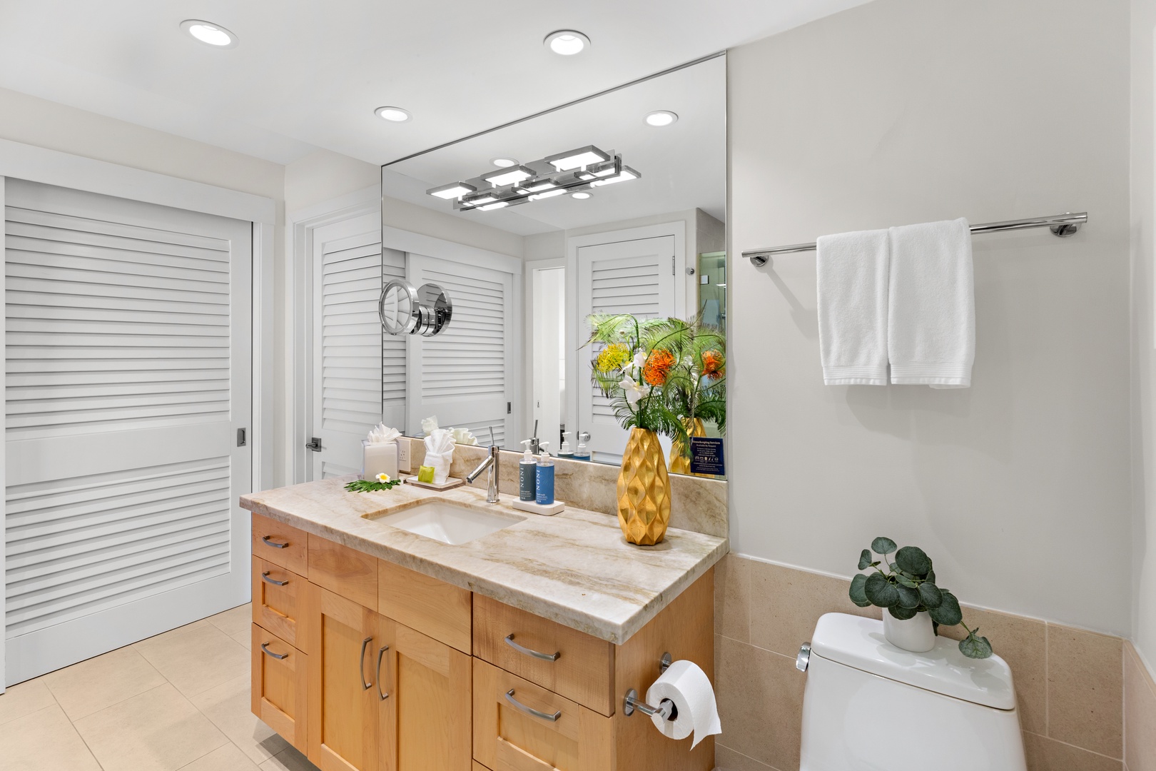 Your beautifully appointed bathroom offers a luxurious marble vanity, warm wood cabinetry, and fresh florals that make every morning feel like a spa retreat.
