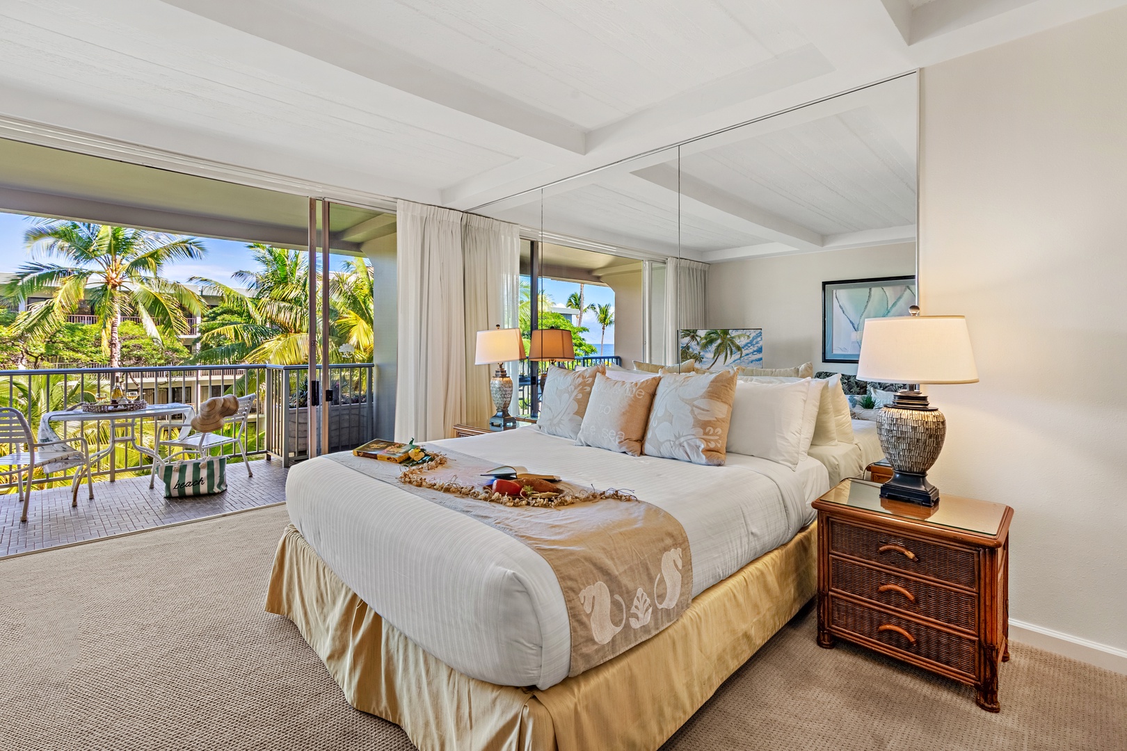 Your tropical bedroom suite features crisp white linens and vibrant blue accents, with floor-to-ceiling windows framing stunning ocean views.