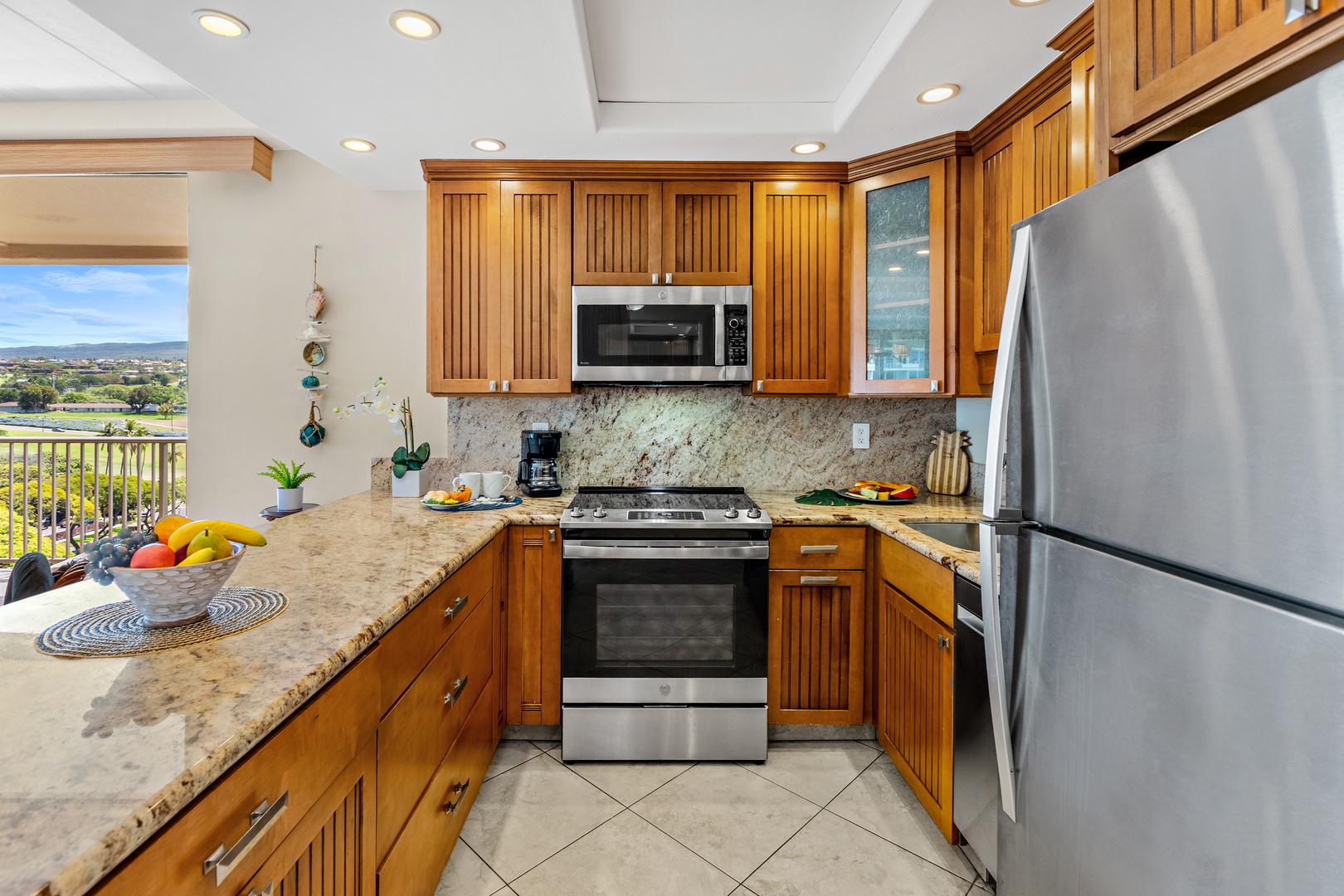 Cook meals with ease in your fully equipped kitchen featuring granite countertops, stainless steel appliances, and scenic views through the window.