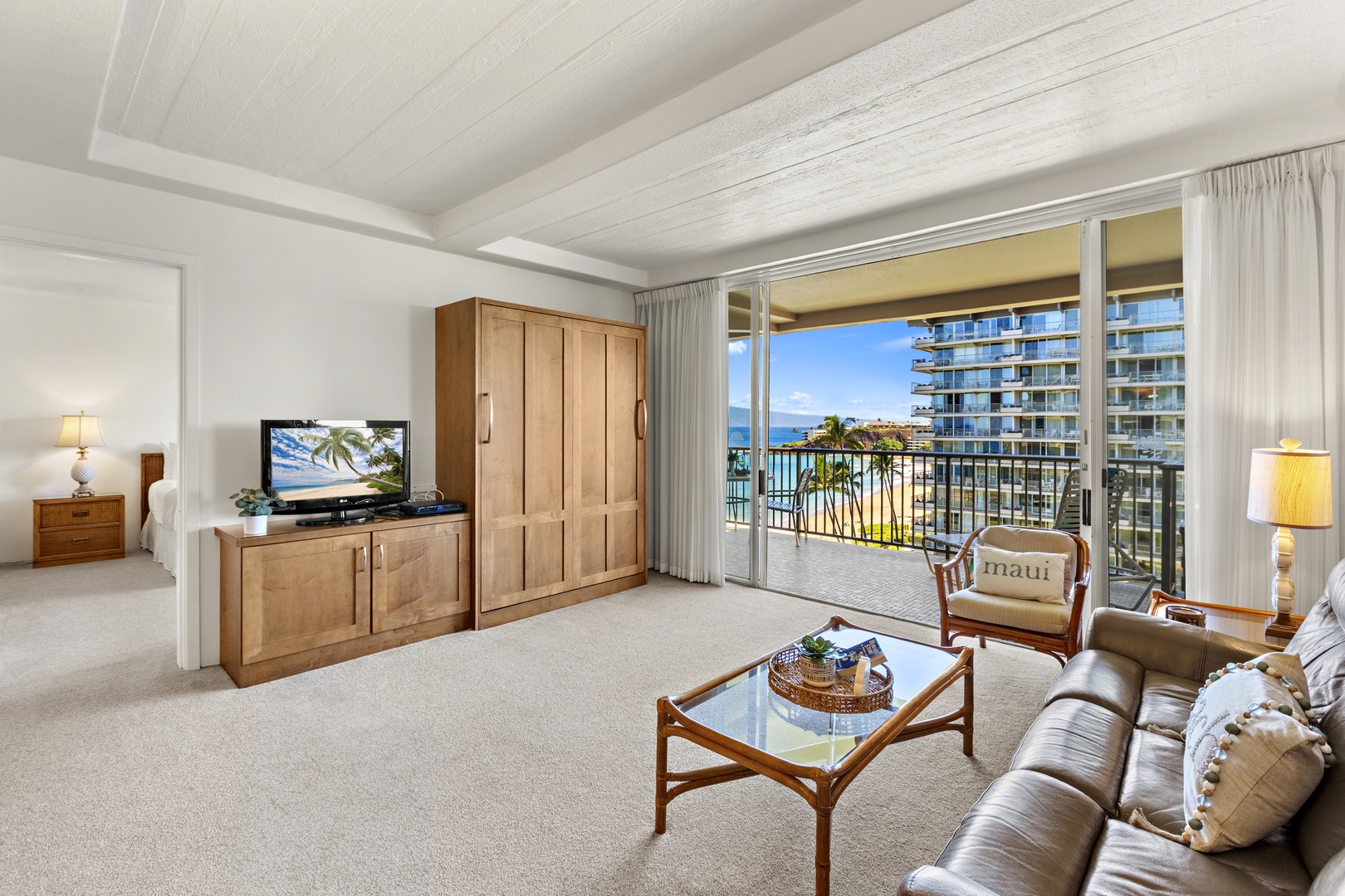 Open-concept living area with a TV console, cozy seating arrangement, and easy access to the furnished balcony.