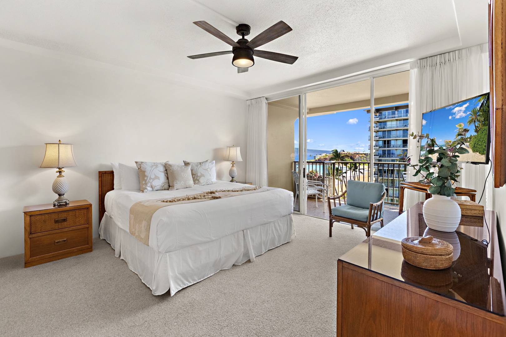 Serene king bedroom featuring crisp white linens, ceiling fan, and bright windows overlooking resort views.