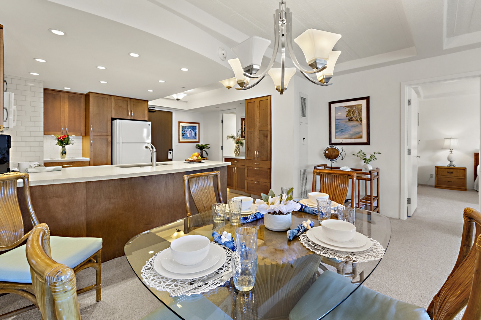 Elegantly set dining table with glass top, upholstered seating, and overhead lighting, creating an inviting space for meals.