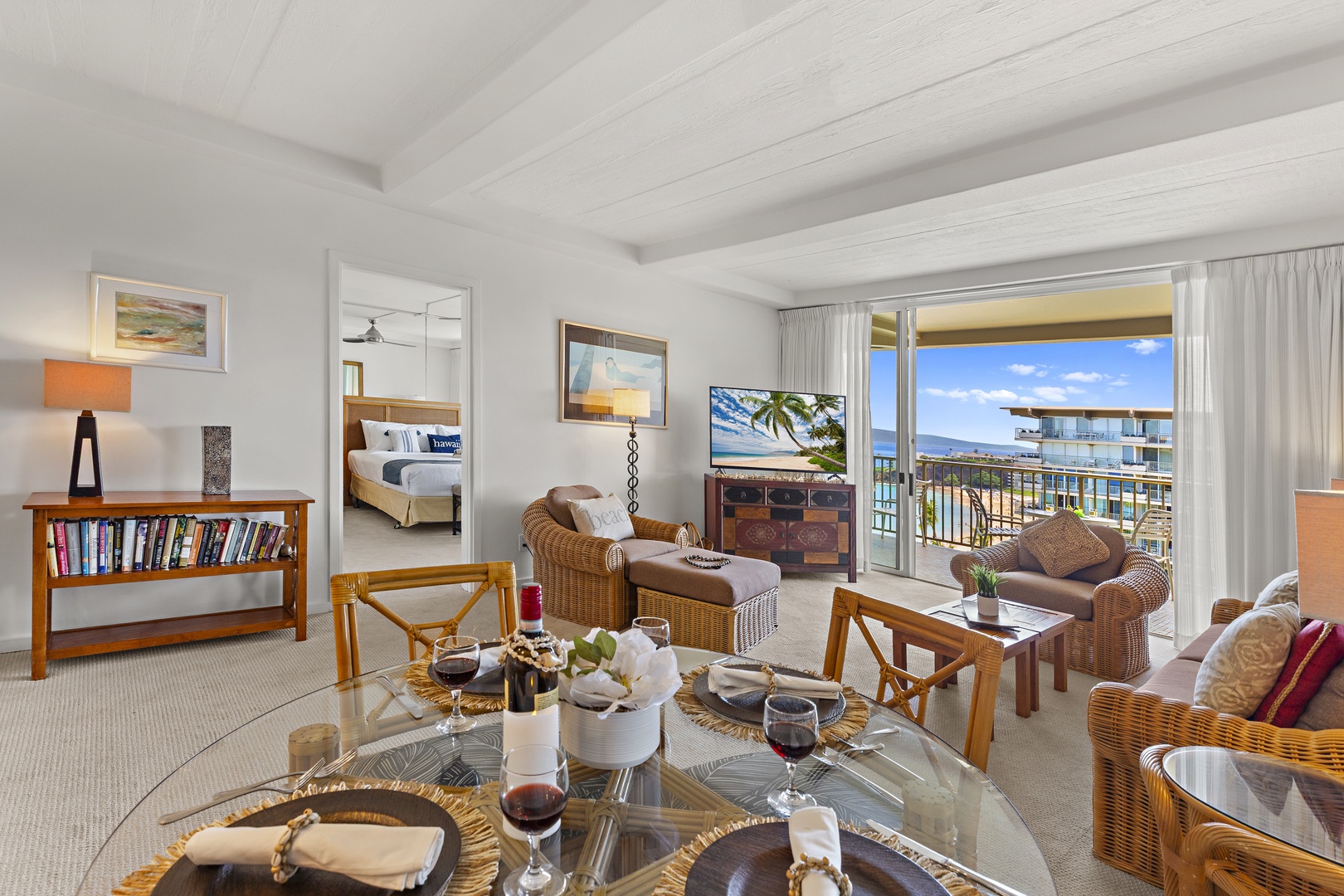 Relax in your spacious living area with wicker furnishings, where your private balcony opens to stunning ocean and mountain views—perfect for unwinding with a glass of wine.