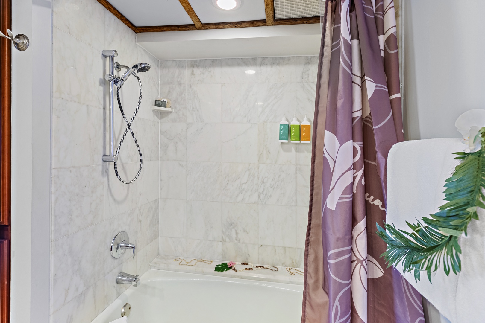 Unwind in your elegant marble bathroom, featuring a spacious tub-shower combo with handheld showerhead and plush tropical-inspired linens waiting for you.