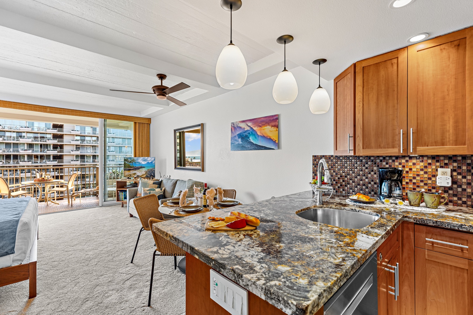 Your open kitchen features granite counters, rich wood cabinetry, and a colorful mosaic backsplash. Pendant lights illuminate the space, while ocean views invite you to start your morning with fresh coffee and coastal breezes.