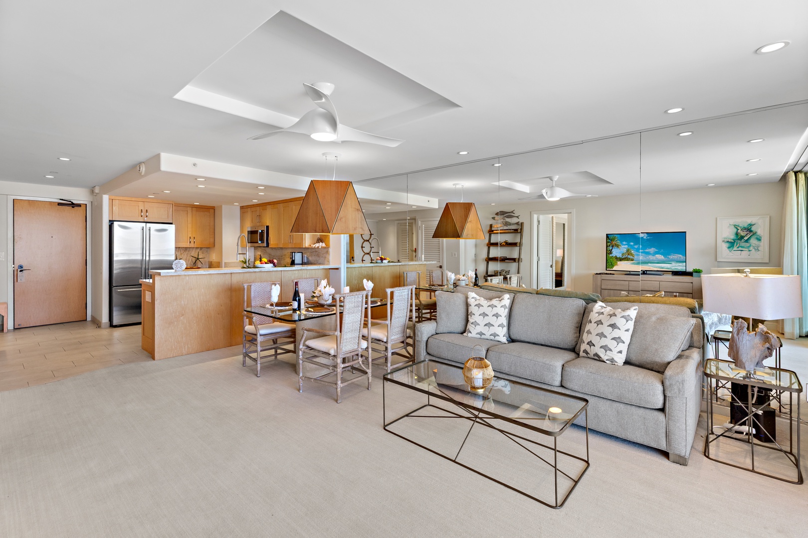 Relax in your open-concept living space, where coastal elegance meets modern comfort. Sunlight pours through the space, highlighting sleek furnishings and your fully-equipped kitchen—perfect for unwinding after beach adventures.