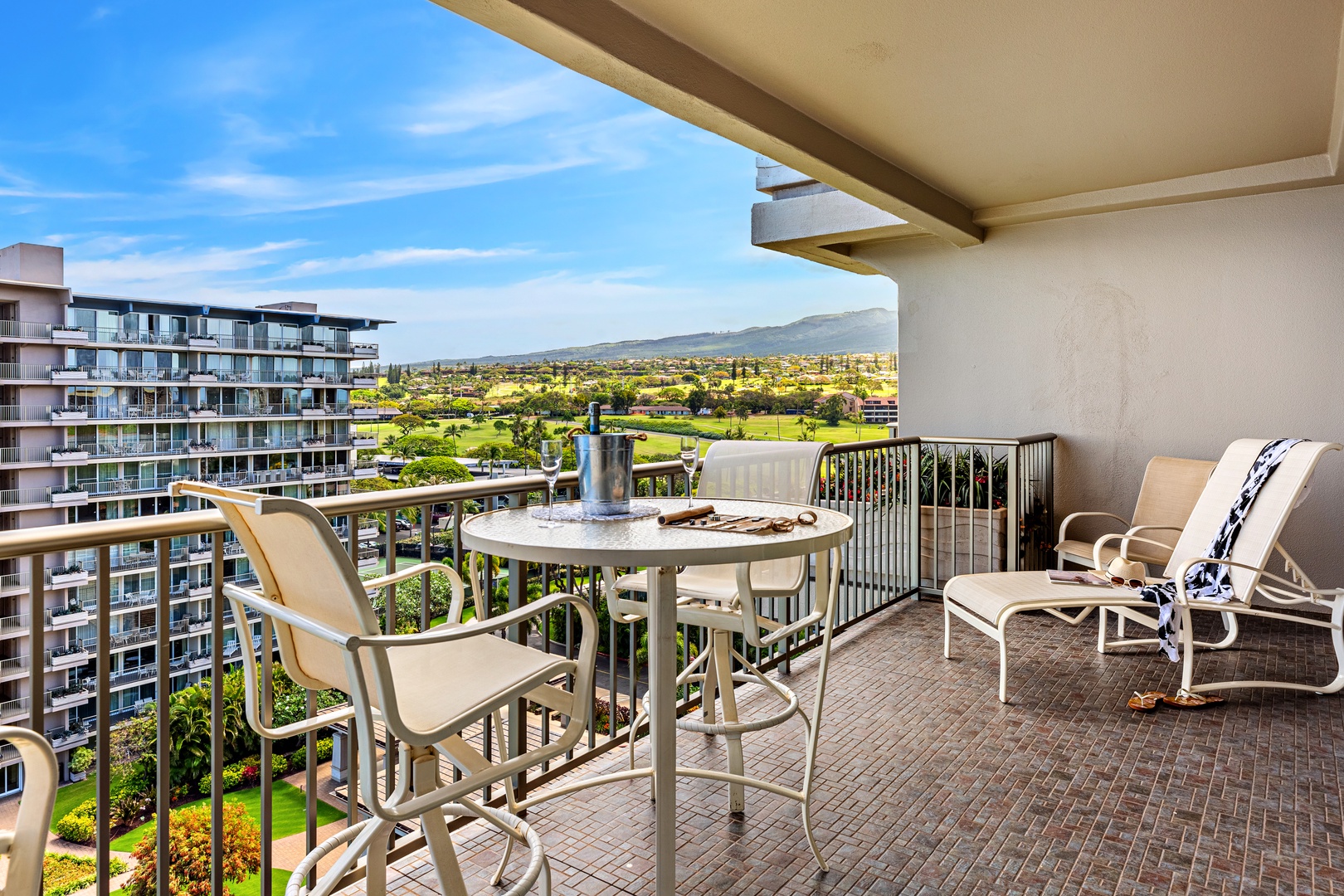 Expansive balcony with panoramic views of lush landscapes and distant mountains, featuring comfortable seating for relaxation.