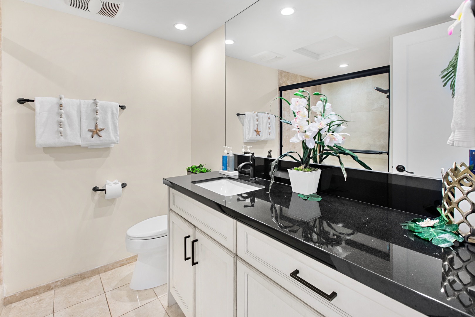 Step into your beautifully appointed bathroom, where crisp white towels, coastal accents, and sleek black countertops create a spa-like retreat for your stay.