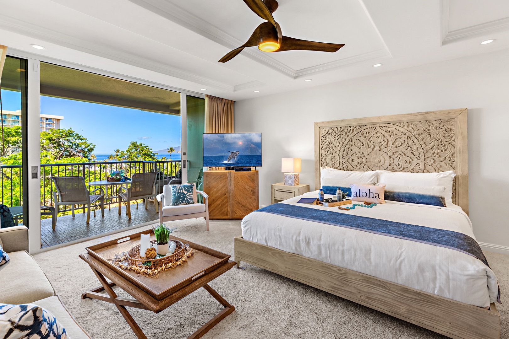 Your bright, island-inspired bedroom invites you to unwind on plush bedding while ocean breezes drift through the open balcony, where lush greenery frames sparkling sea views.