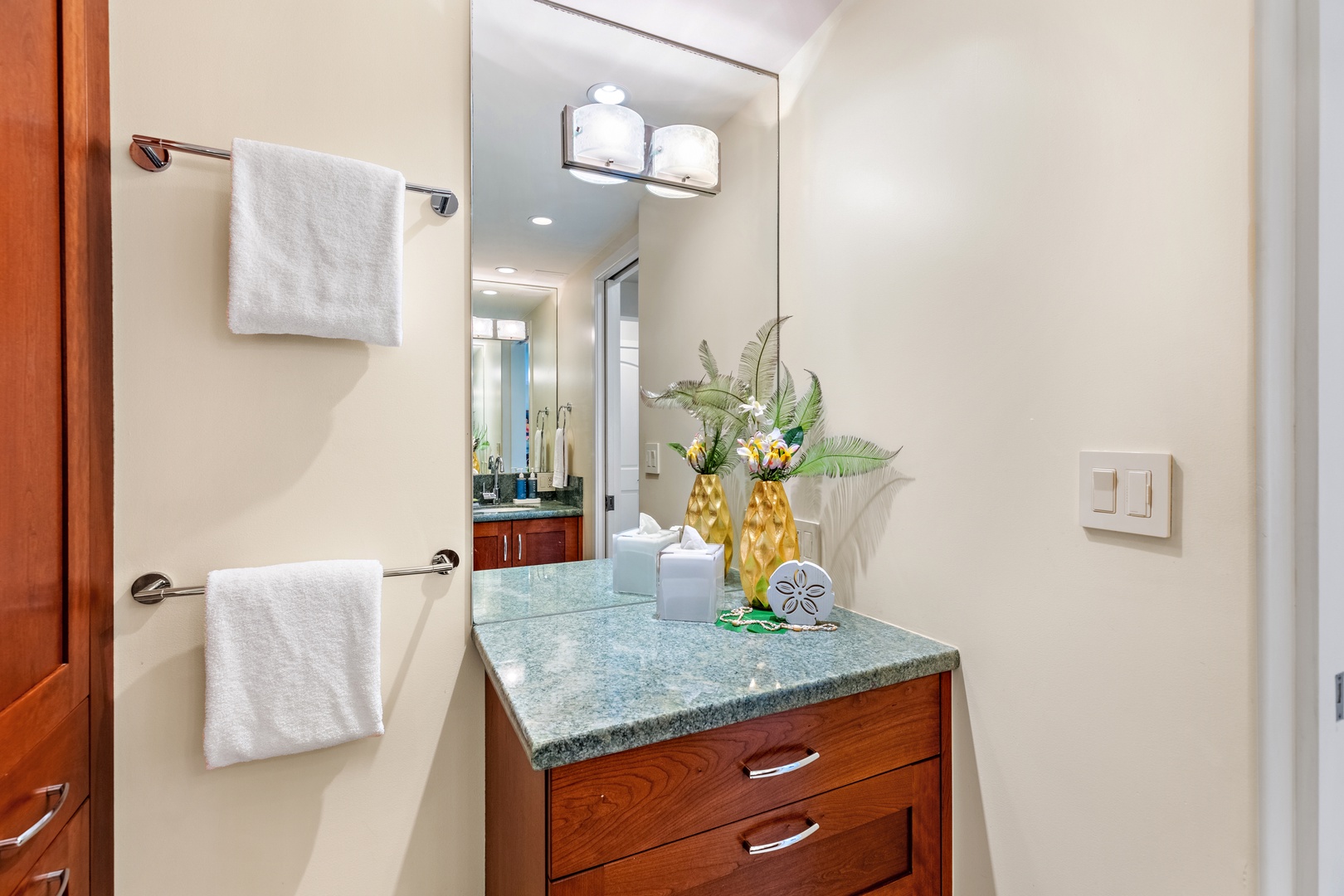 Step into your private retreat with coastal charm—a sleek vanity topped with calming blue granite, fresh white towels, and cheerful tropical touches that instantly put you in vacation mode.