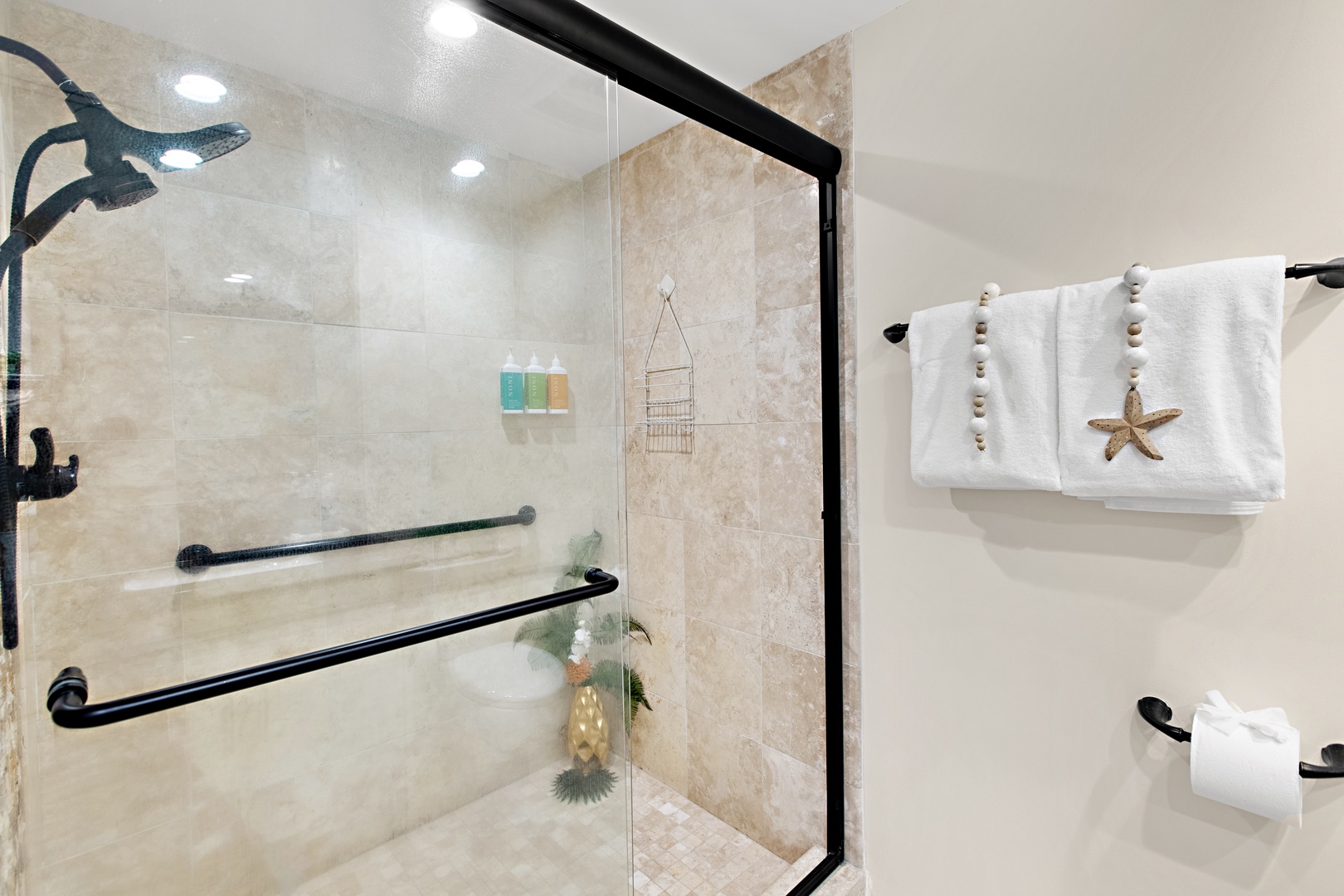 Step into your spacious walk-in shower with dual grab bars for safety and comfort. Fresh toiletries await, and soft towels with coastal details add a welcoming touch to your private bathroom.
