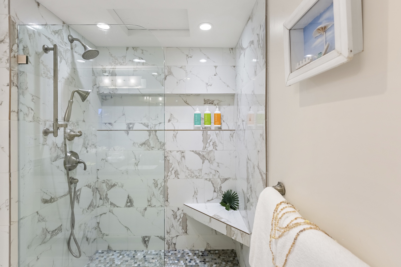 Contemporary walk-in shower with marble-style tile, built-in bench, and rainfall showerhead for a spa-like retreat.