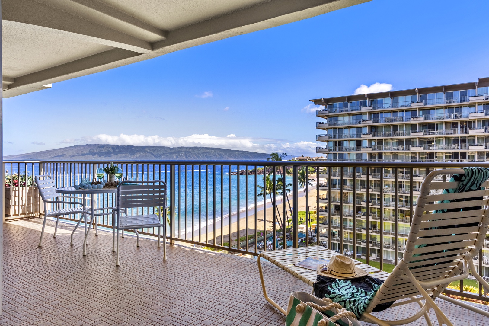 Spacious balcony with outdoor seating, offering uninterrupted views of the Pacific and neighboring beachfront resort.