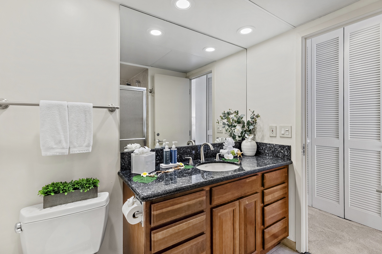 Step into your own spa-like retreat with gleaming granite counters, warm wood cabinetry, and thoughtful touches like fresh flowers and plush towels waiting for you.